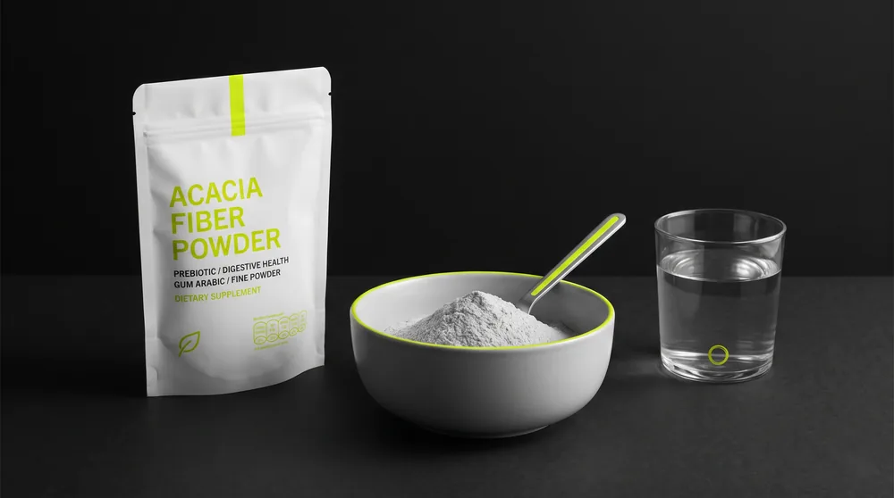 Acacia fiber powder (gum arabic) in a bowl with a spoon next to a glass of water on a dark surface