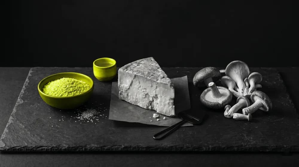 Weizenkeime, gereifter Kaese und Pilze auf dunkler Matte als natuerliche Spermidin-Quellen