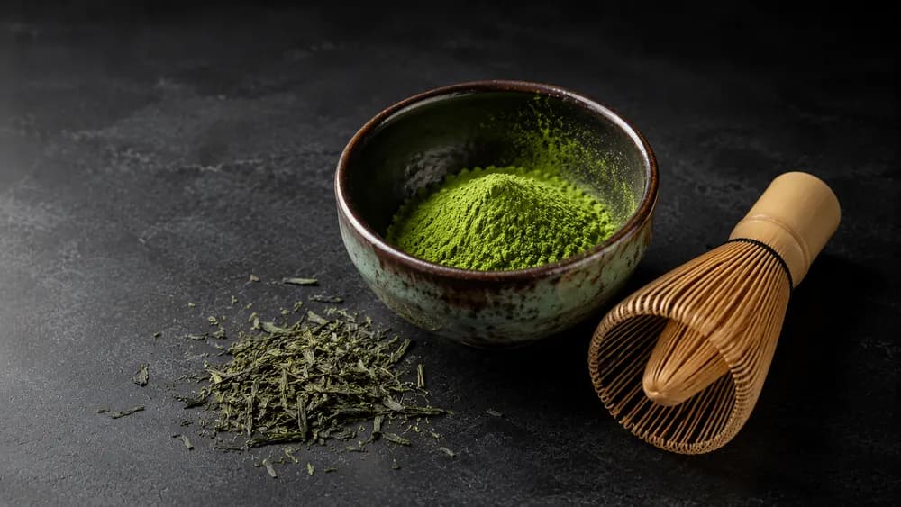 Matcha-Schale mit Bambuslöffel und Grüntee-Blättern
